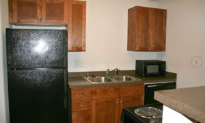 Kitchen with black appliances and cherry-wood cabinetry in our Lawrence apartments.