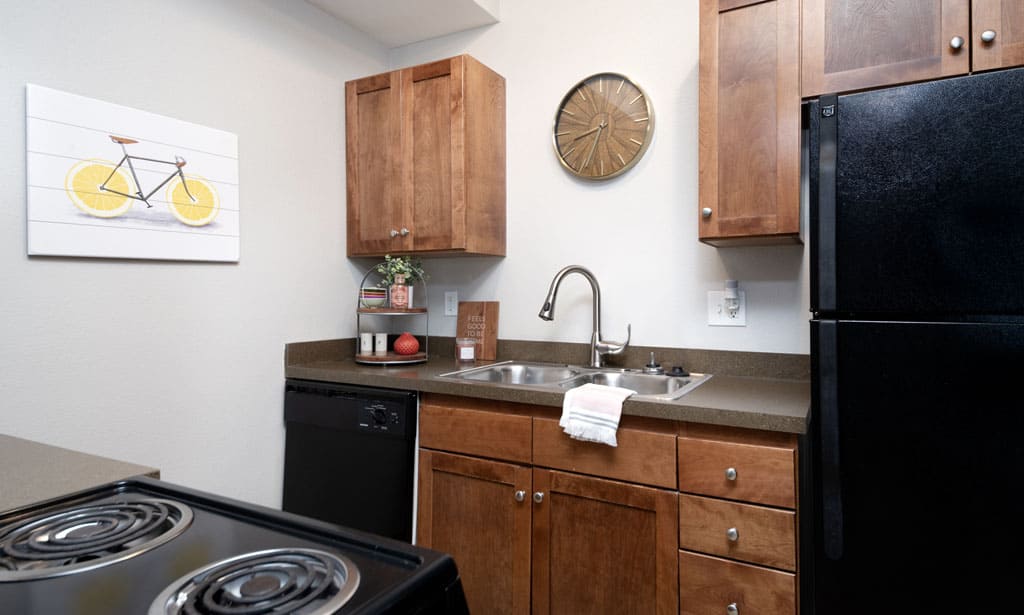 Kitchen with black appliances and cherry-wood cabinetry in our Lawrence apartments at Remington Square